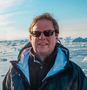 A person poses by a harbor.