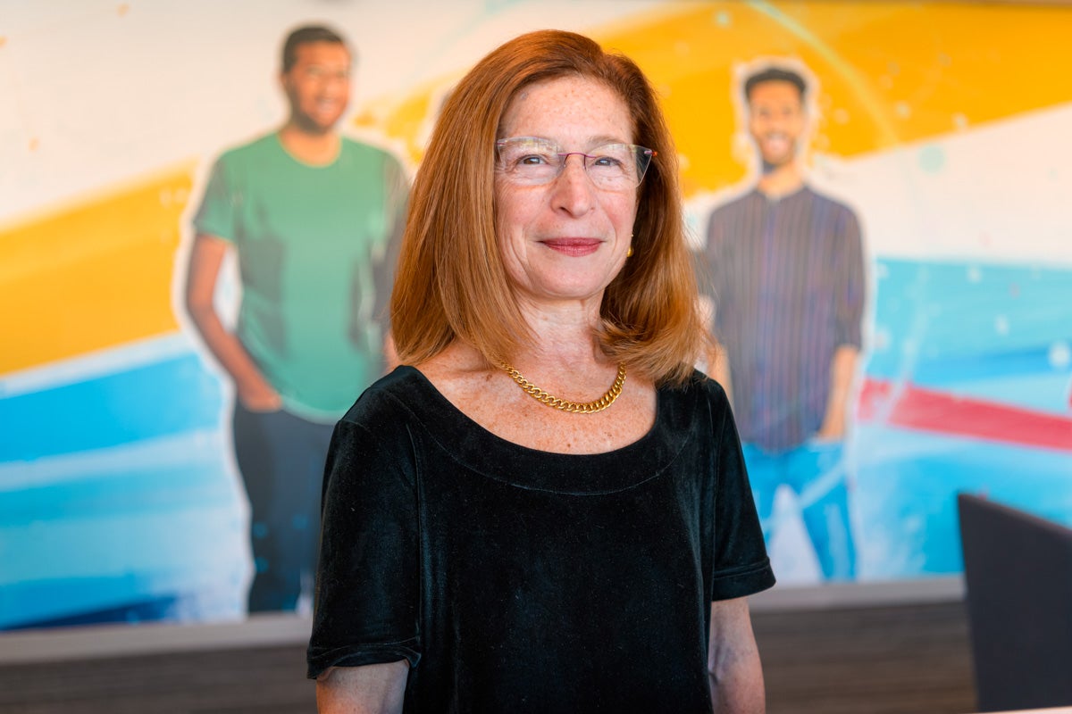 Leslie Hyman standing in front of a mural showing three people.