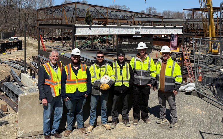 construction team stands in front of building under construction