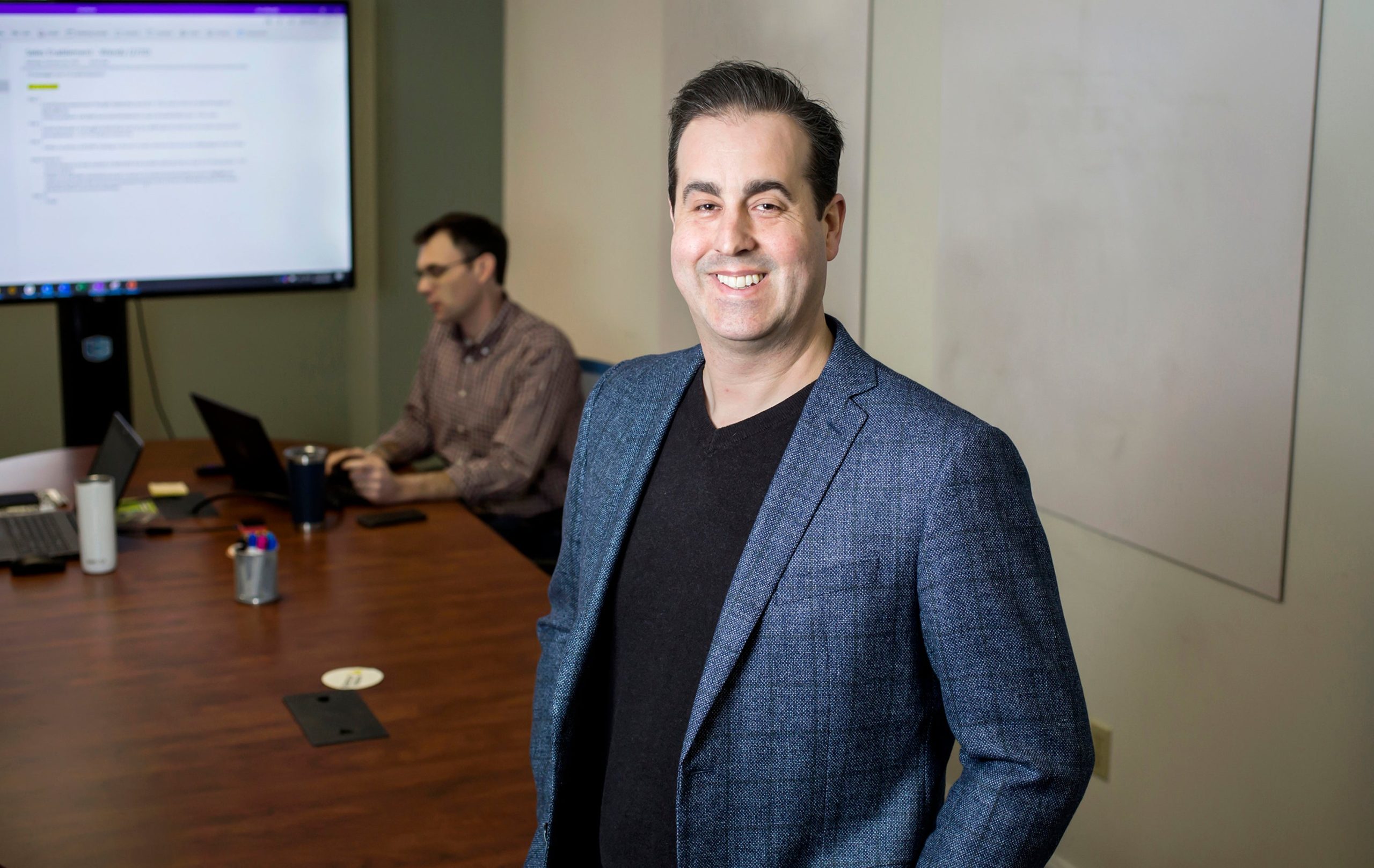 Rob Simopoulos of Defendify, with a person at a laptop in the background.