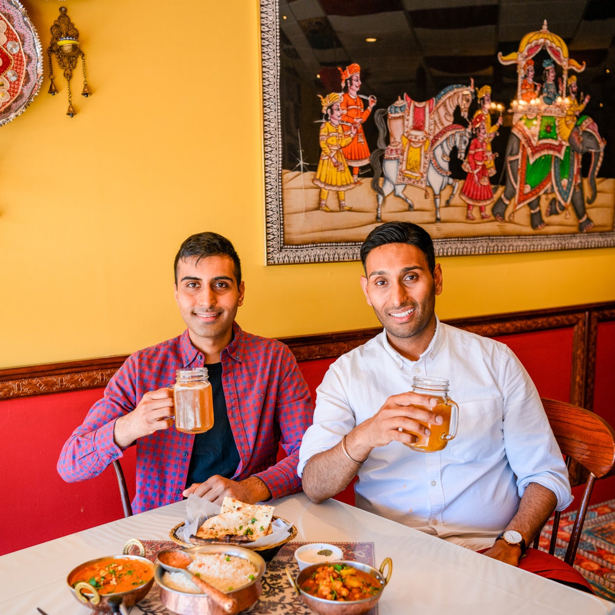 Van and Sumit Sharma at Indian restaurant holding up glasses with beer