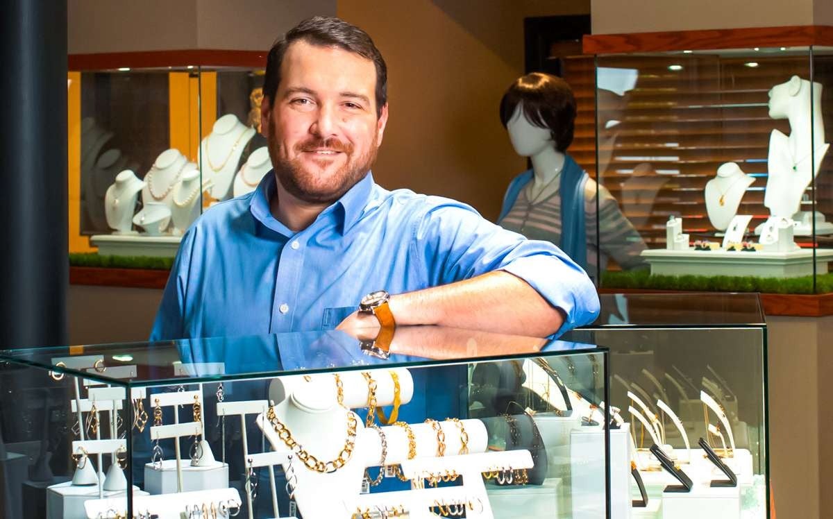 person in blue shirt with jewelry in glass cases