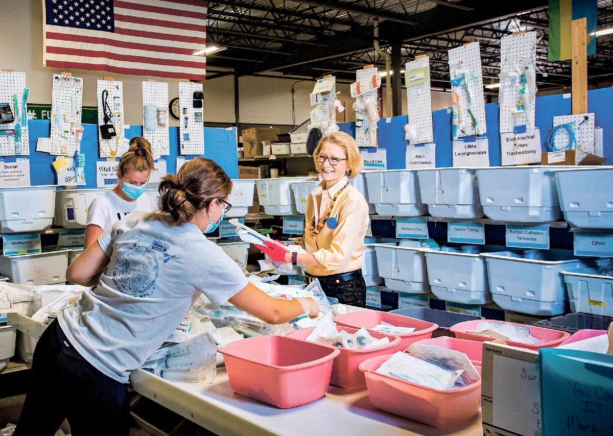 Elizabeth McLellan of Partners for World Health with volunteers in sorting warehouse.