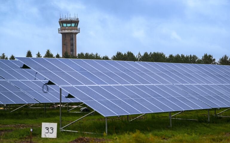 Solar panels in foreground, control tower in background, at the former Loring Air Force Base.