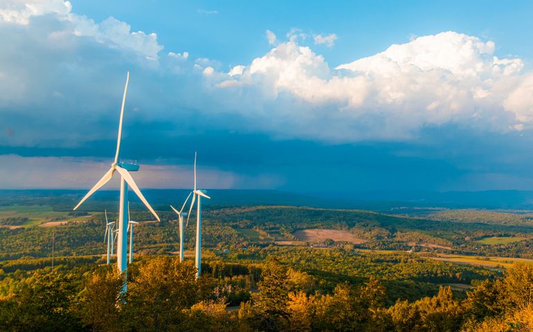 Two windmills with clouds on hill