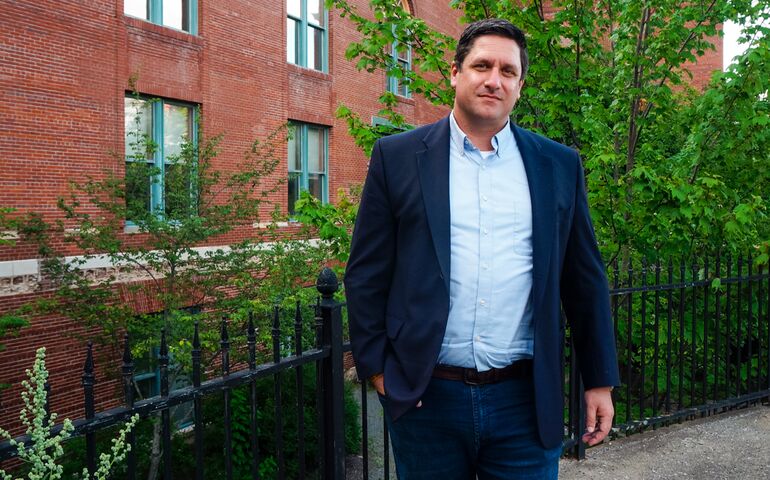 man in blue blazer standing in front of brick building