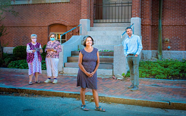 three women and a man standing outside a brick building