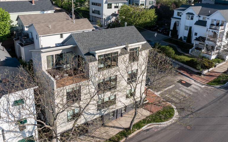 An aerial view shows several buildings, streets and trees