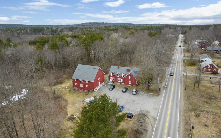 aerial of two red buildings woods and road