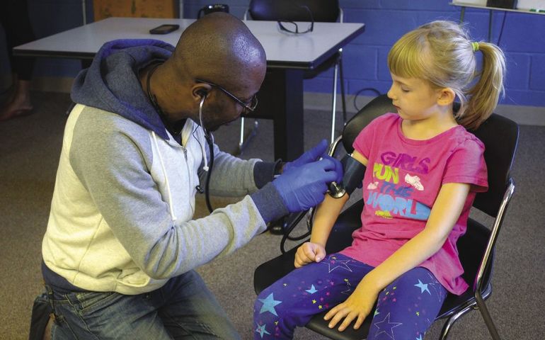 A man checks the blood pressure of a young girl