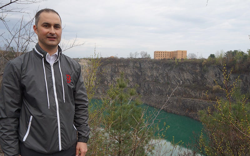 a white man stands next to a weedy quarry