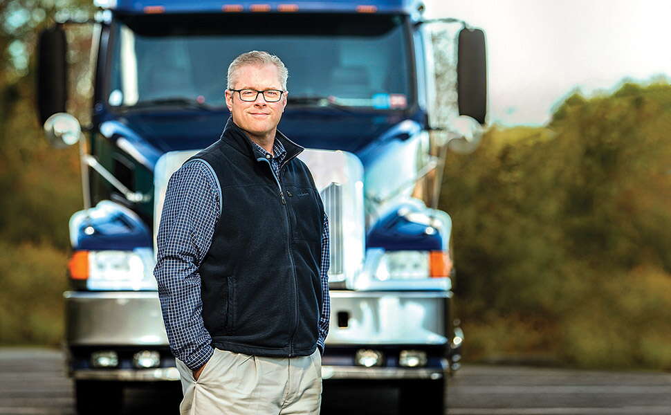 A person stands in front of a truck.