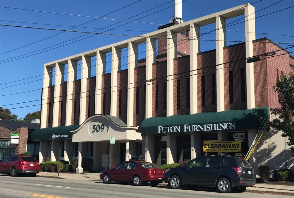 A brick building has pillars and awnings.