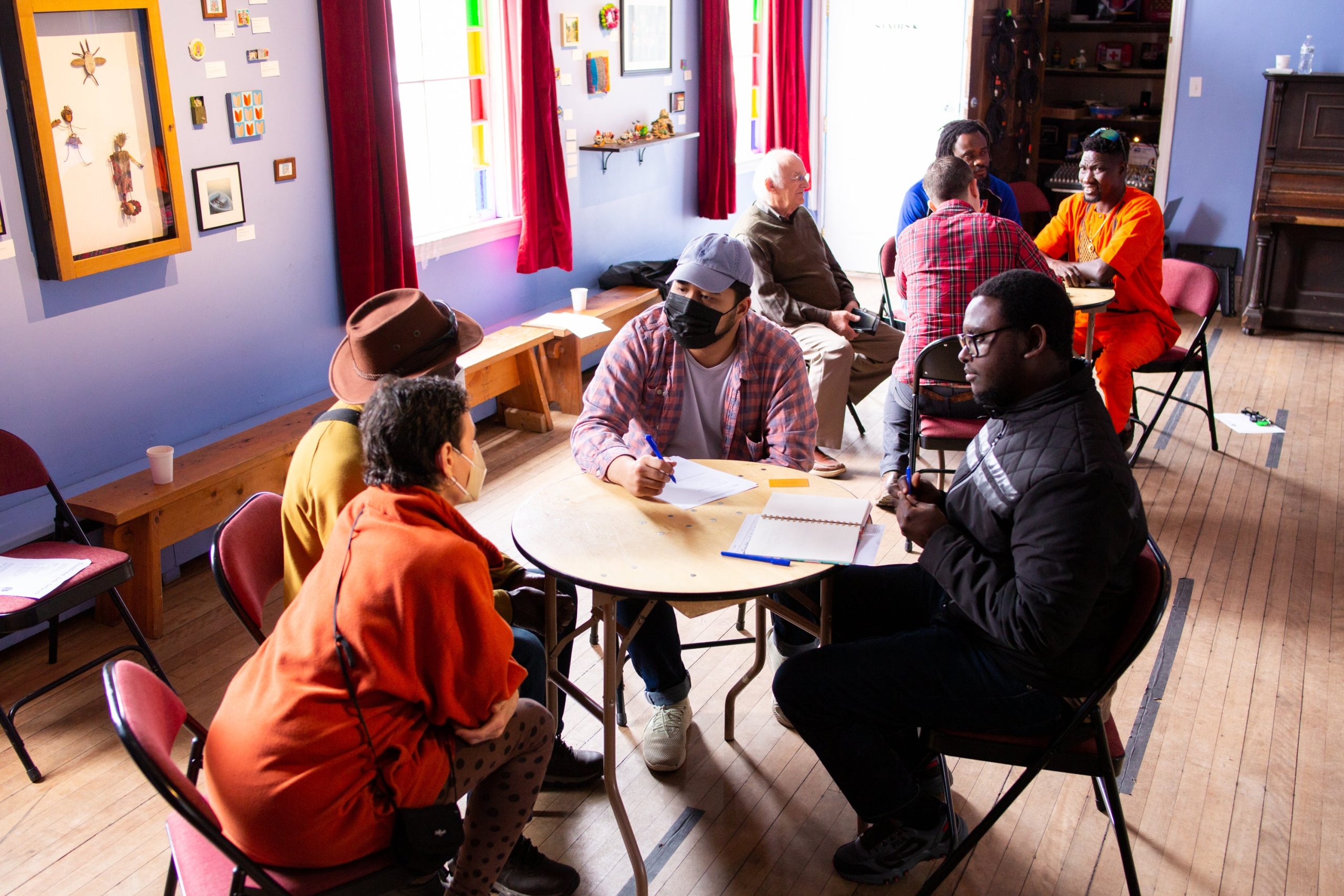 A group of people talk at tables at Mayo Street Arts.