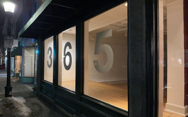 A nighttime view of the exterior of large storefront windows.
