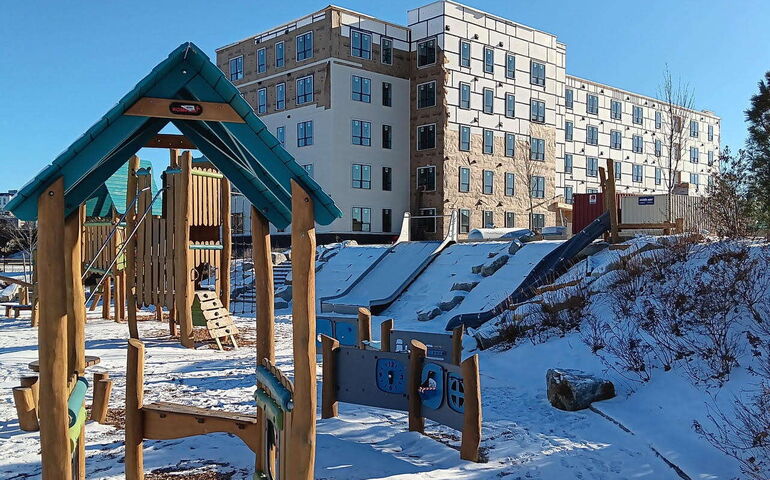 A playground is in front of a building under construction.