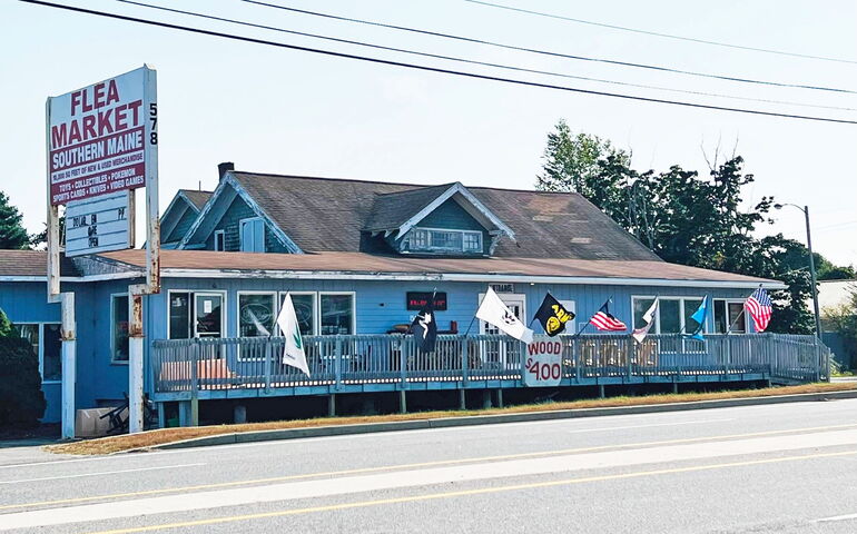 A long blue building includes flags and a railing.