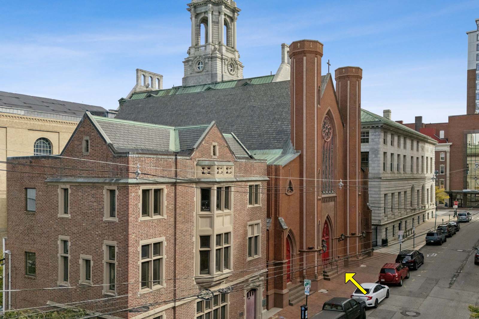 An old brick church and other bulldings line a street.