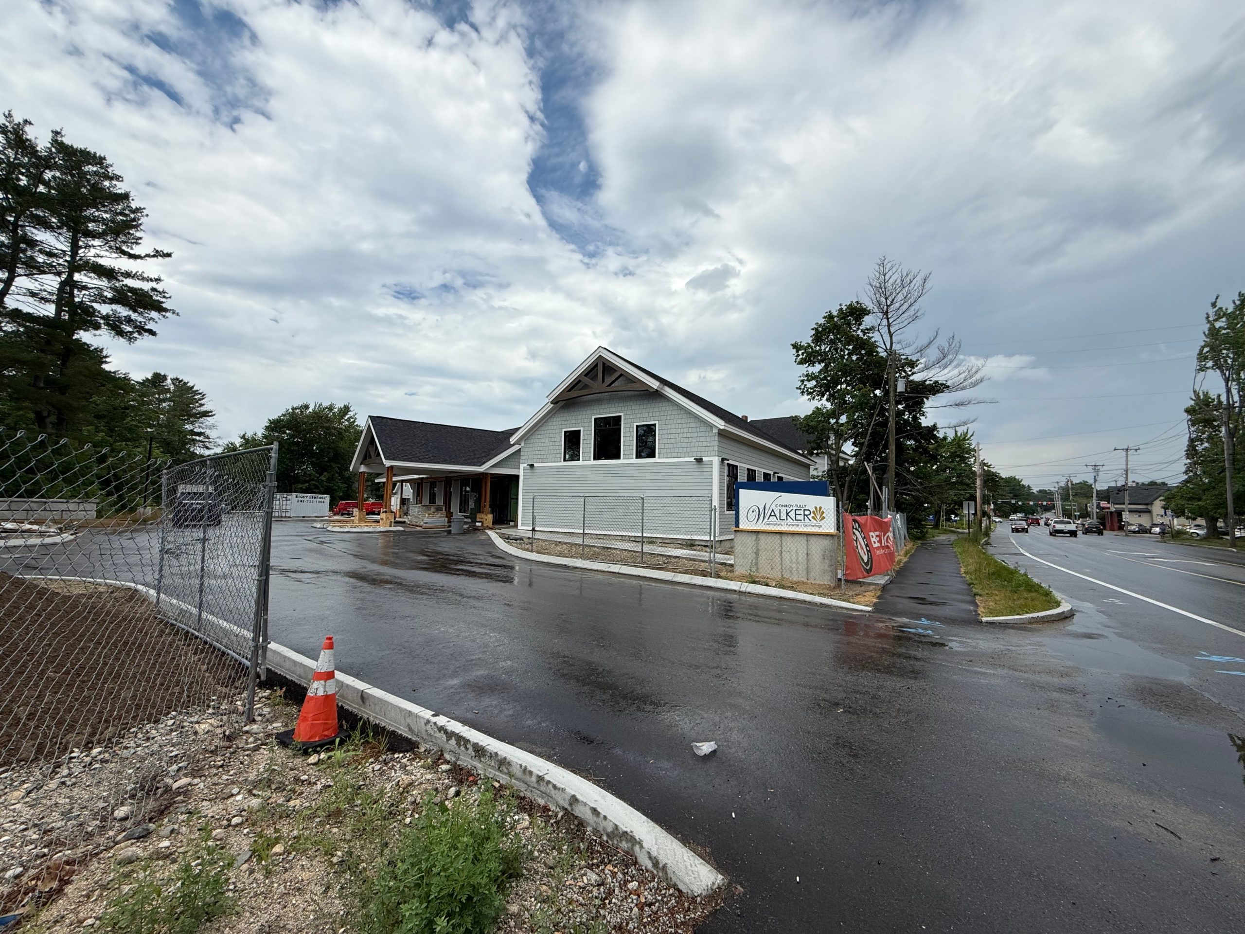 An exterior of a gray-sided building and a road and driveway.