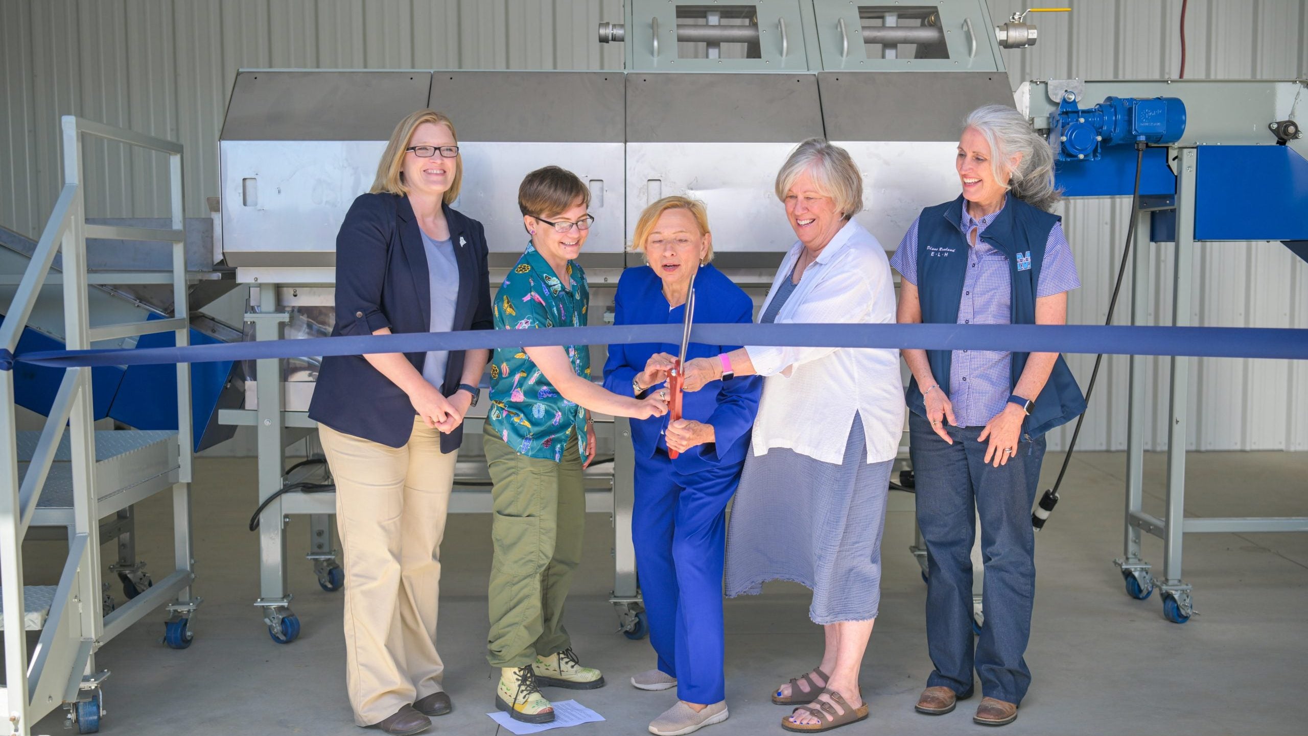 People pose with a ribbon and scissors.