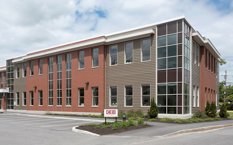 A large modern two story brick and glass building with a sign that says CEI near the front door