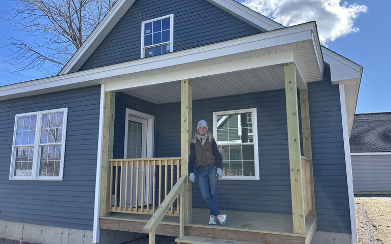 A person leans against a porch post.