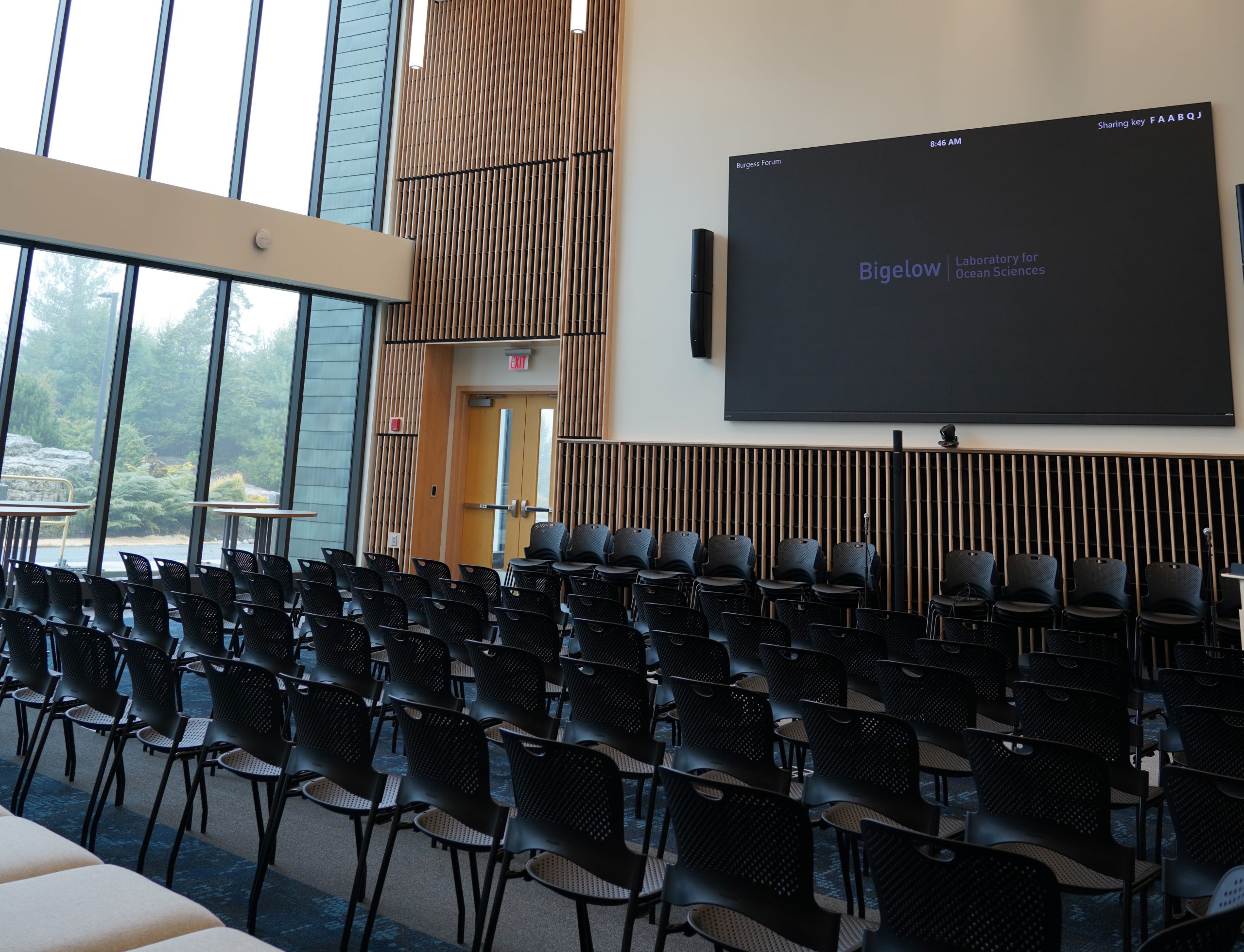 A room has a big screen and lots of chairs in rows.