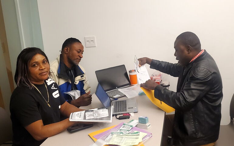 Three people sit around a table with paperwork.