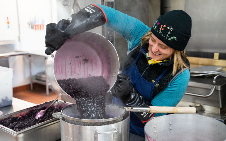 A person pours berries into a strainer.