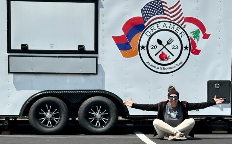 A person sits cross-legged outside a truck.
