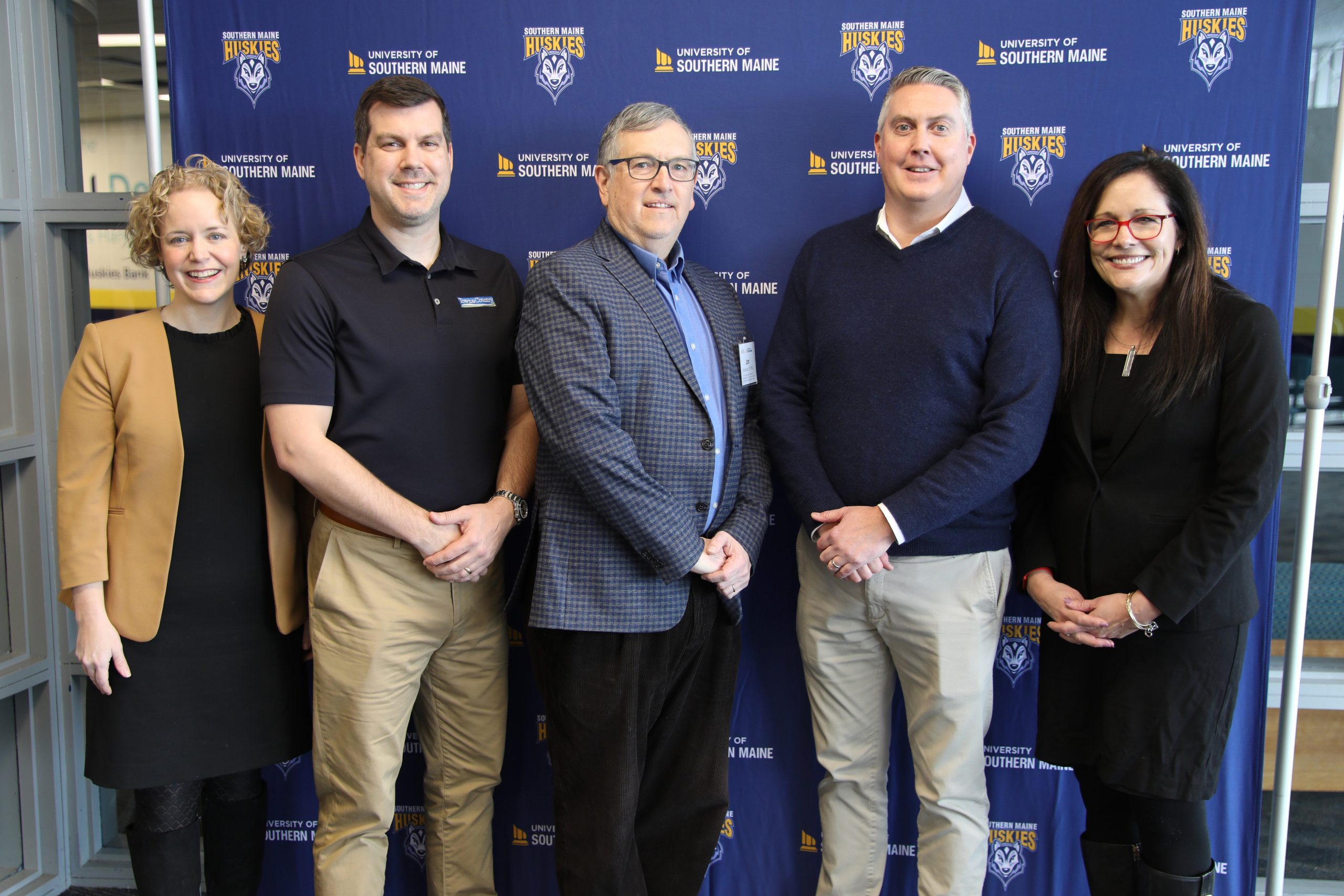 5 people standing in a line in front of banner