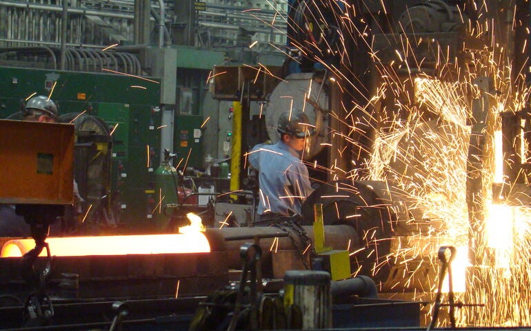 A person works with machinery and there are sparks.