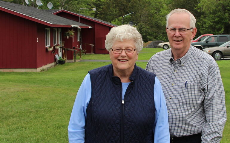 Two people stand on a line outside of an apartment building.
