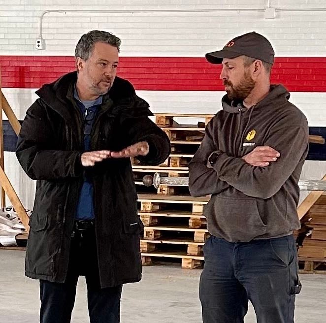 Two people talk inside a warehouse.