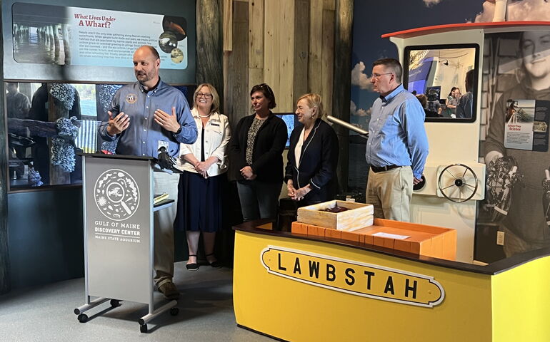 People stand inside the Maine State Aquarium giving a presentation amid some displays.