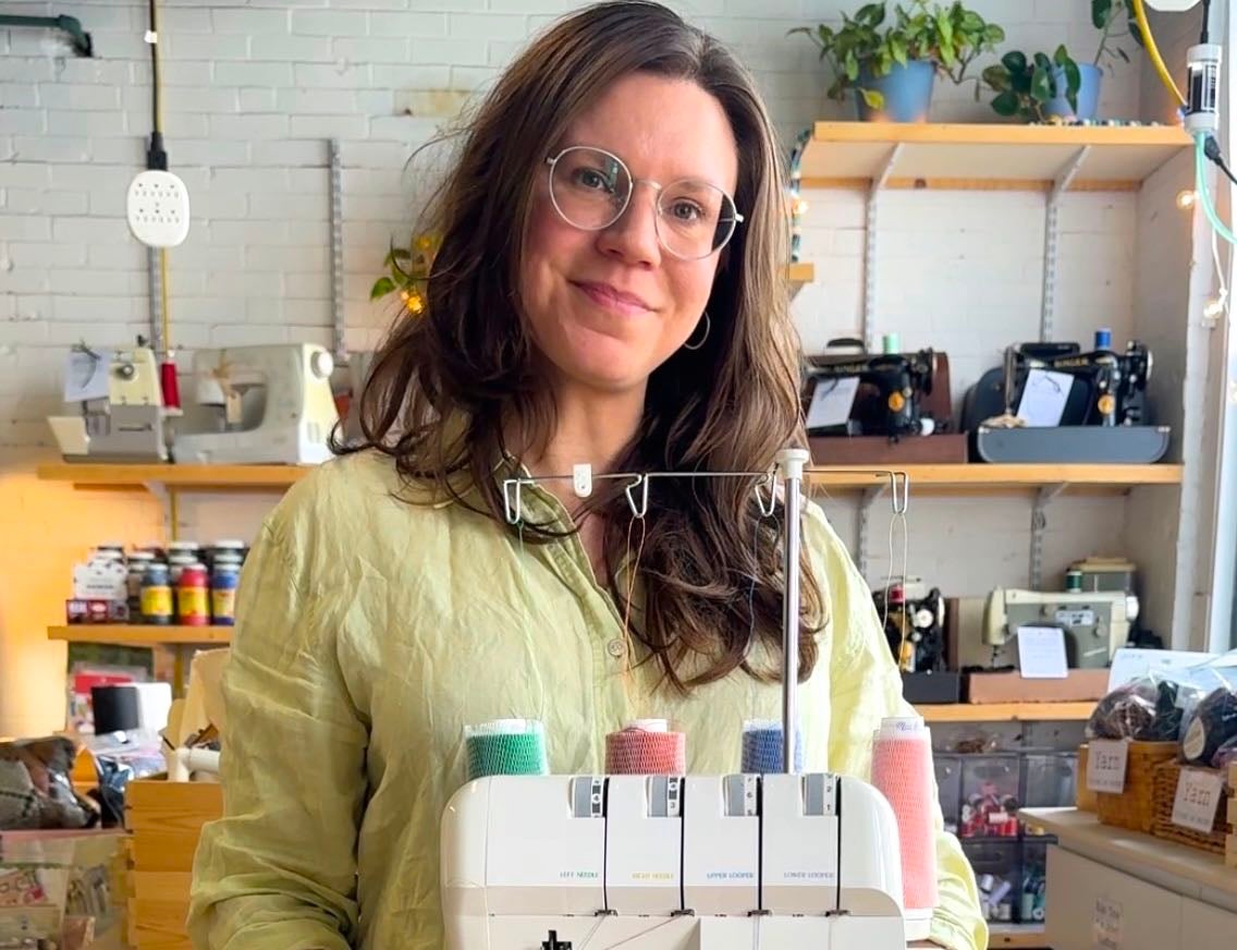 A person stands with a sewing machine.