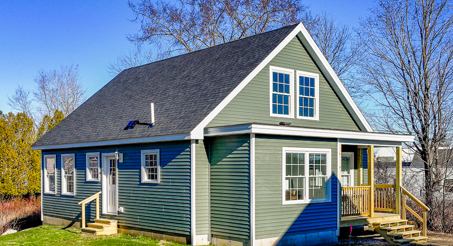 An exterior view of a new house with green siding.