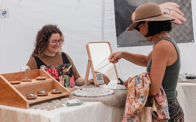 Two people look at artisan wares at a table.
