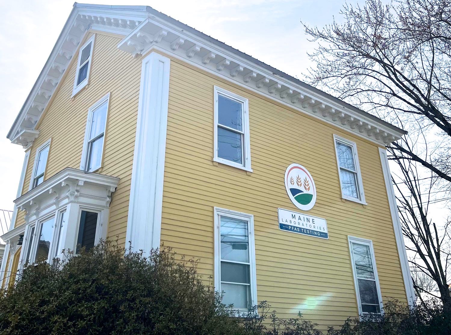 A building has yellow siding and a sign.