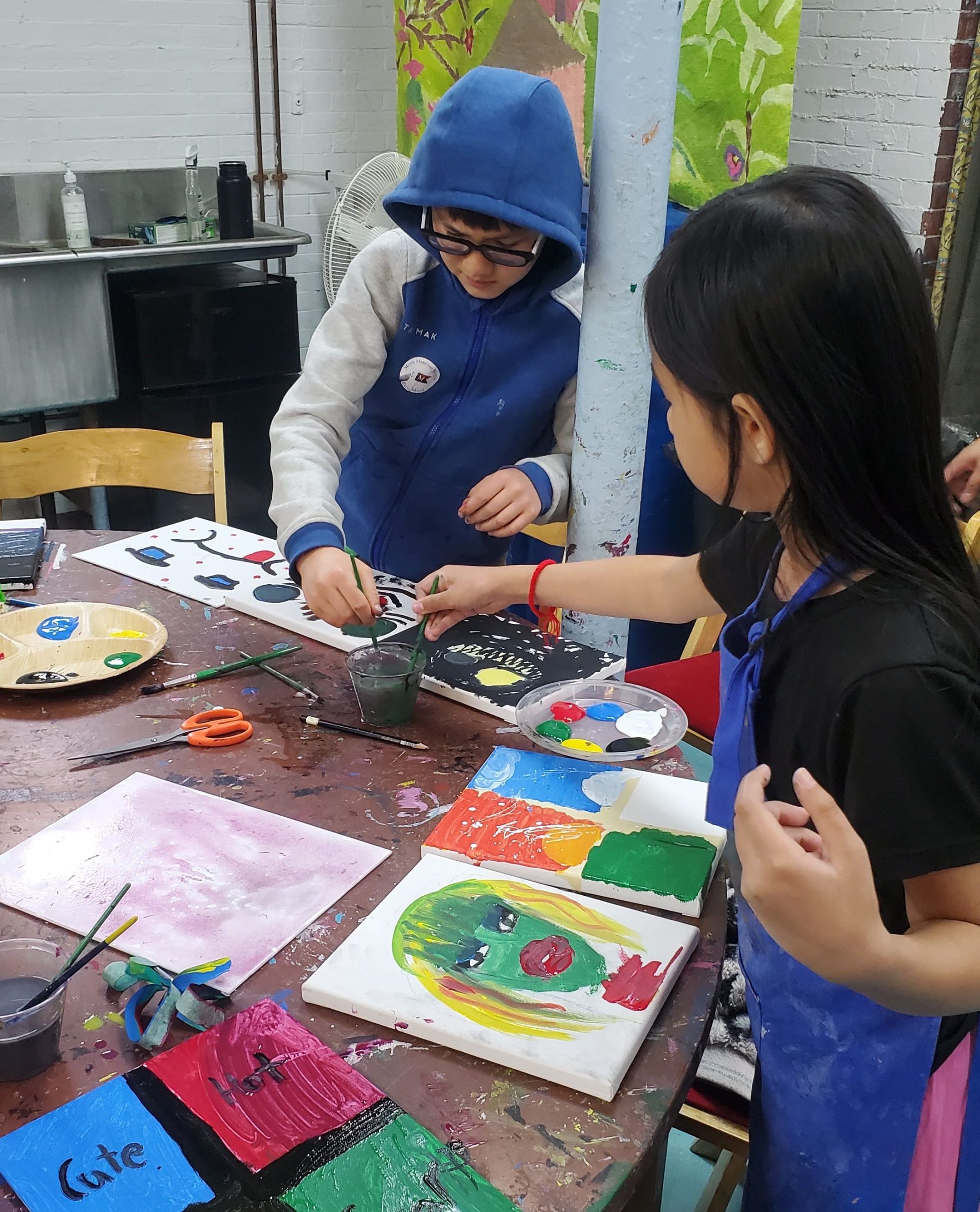 Children paint at a table at Mayo Street Arts.