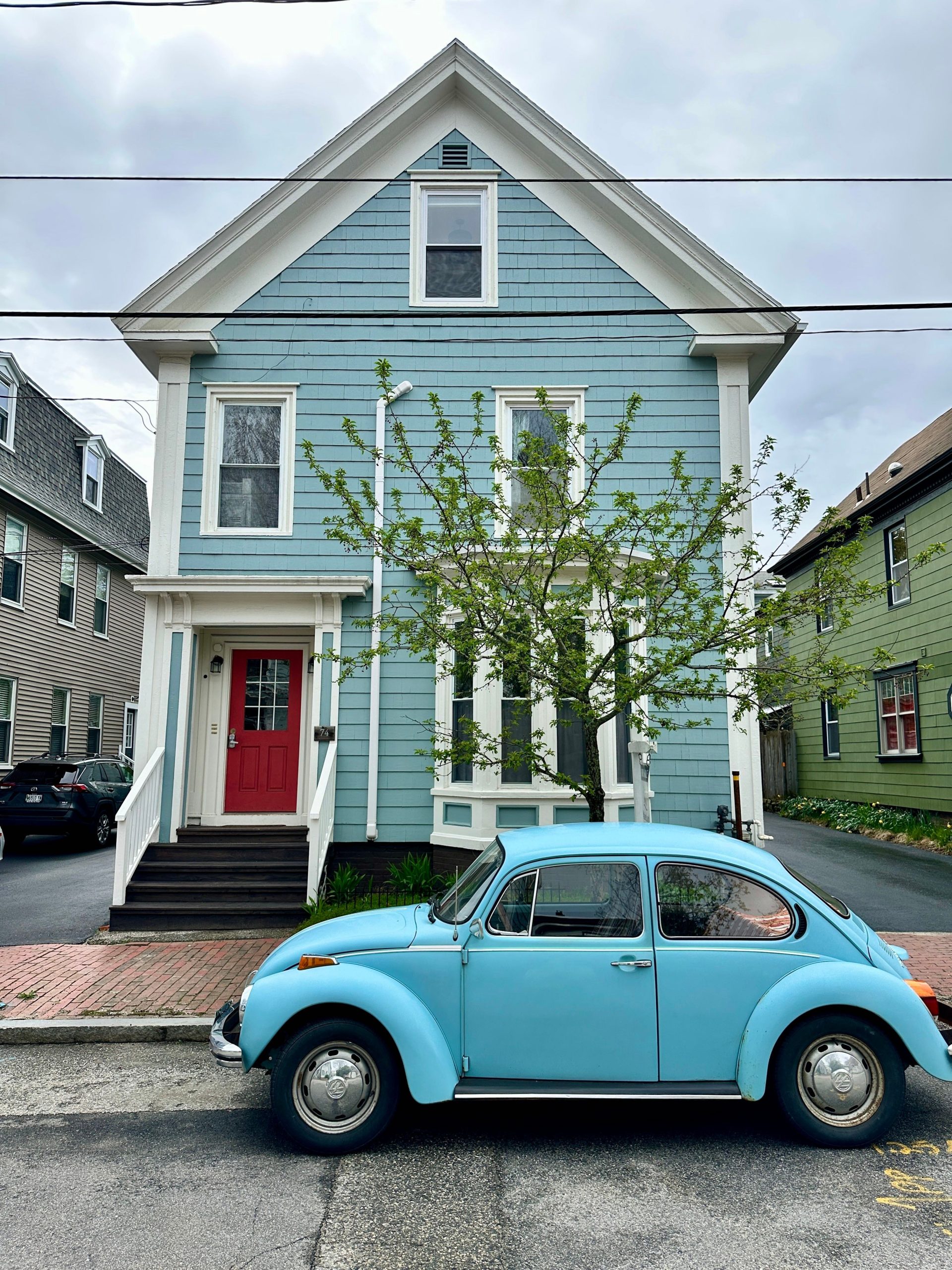 A blue-sided house as a blue VW outside.