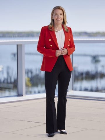 Melissa Smith stands on a deck and wears a red blazer.