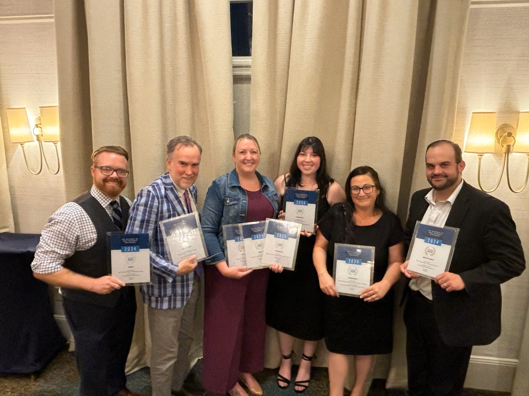 New England Business Media staff members holding awards from the Alliance of Area Business Publishers.