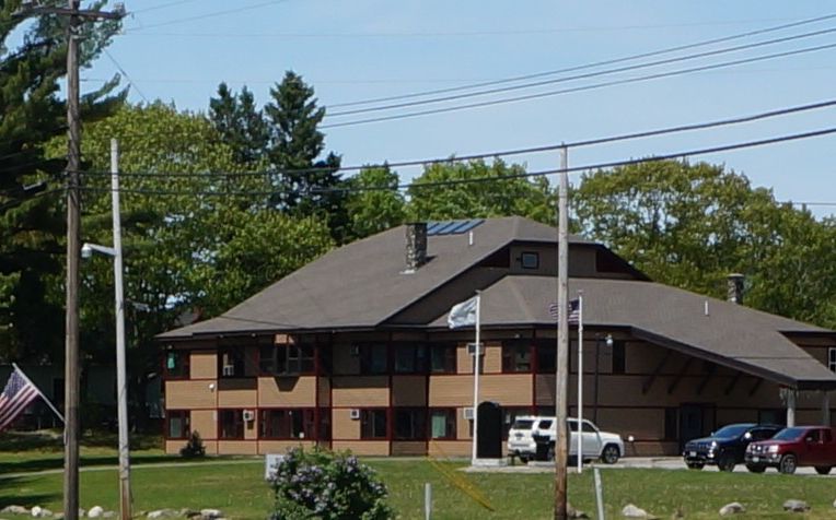 A two-story large brown wooden building with an American flag flying in front