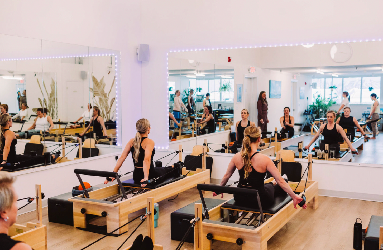 People sit on Pilates tables and look into mirros.