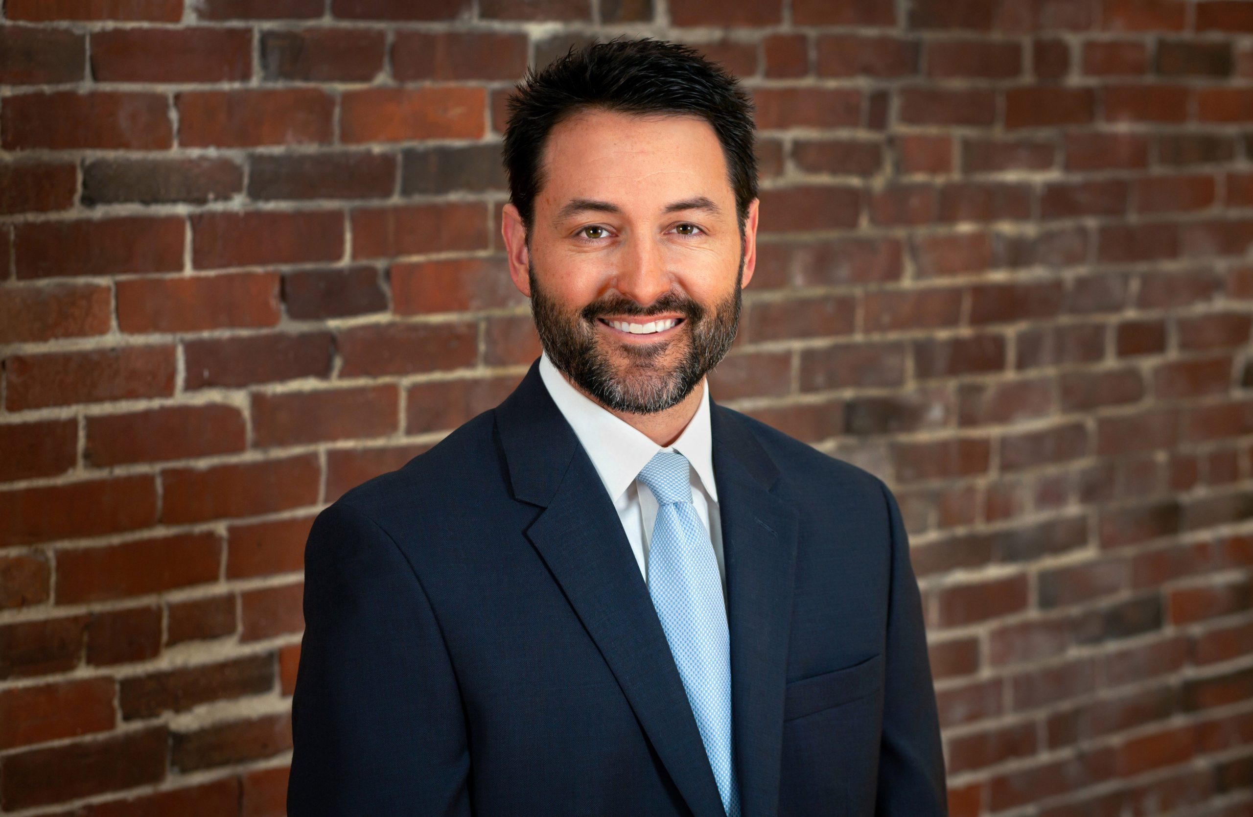 person in suit and tie in front of brick wall