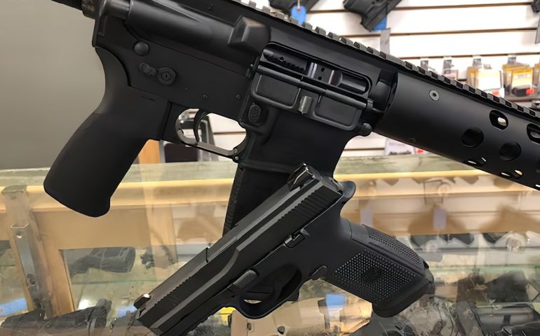 assault rifle and handgun posed on glass counter of gun shop