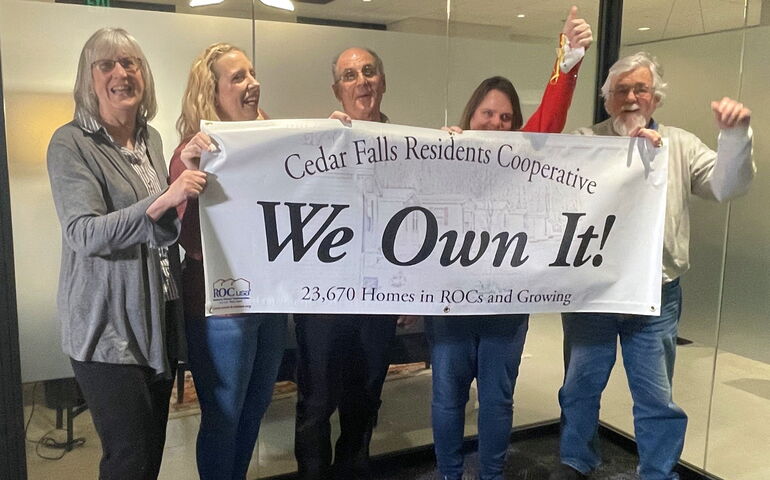 Five people pose with a banner.