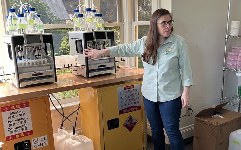 A person stands with some laboratory machinery.