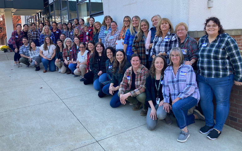 People pose in lines in front of a building.